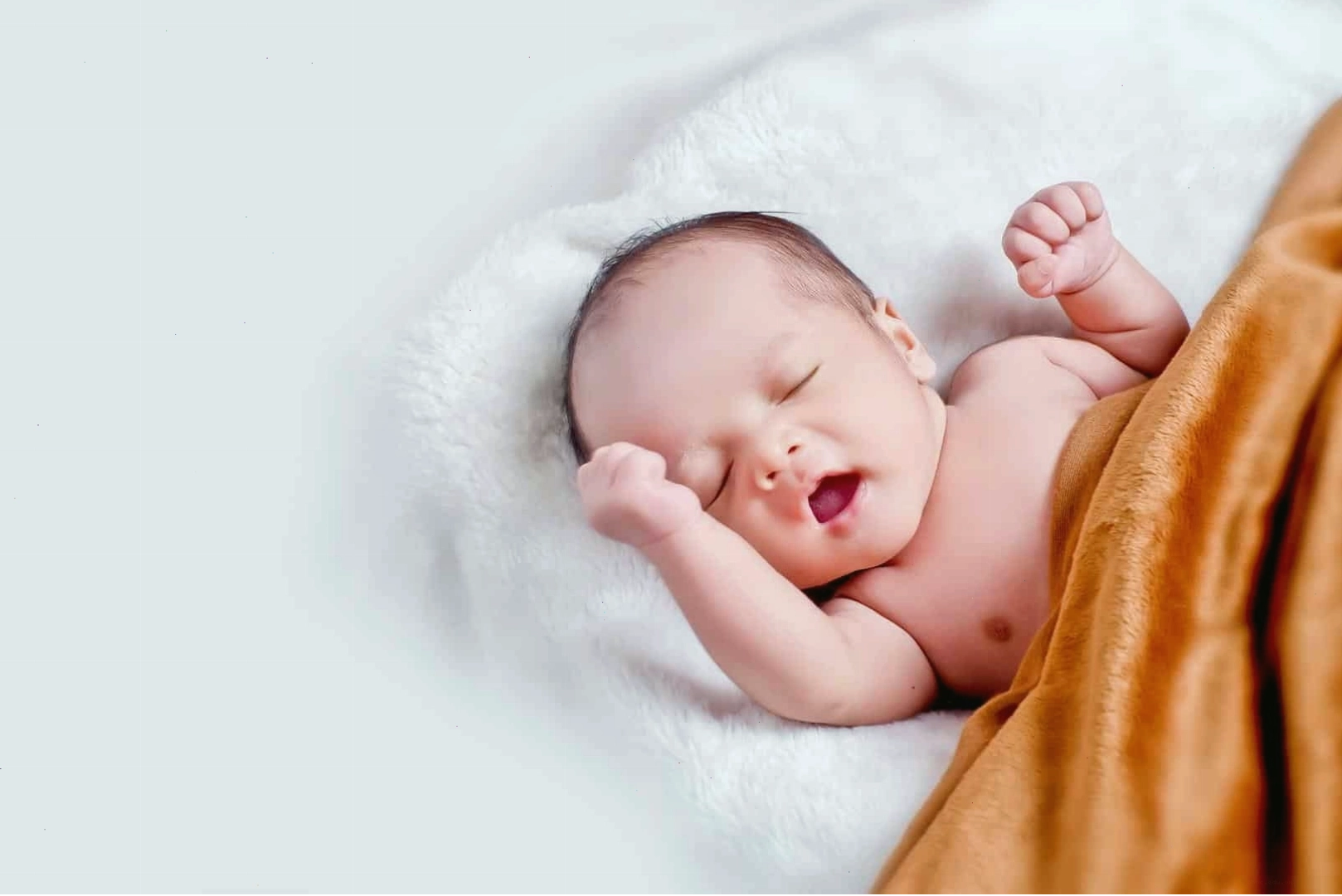 Bé sơ sinh đang mỉm cười nhẹ trong giấc mơ