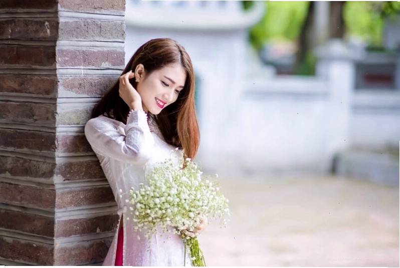 Cô gái cầm bó hoa nhỏ, nhẹ nhàng che đi nụ cười e ấp
