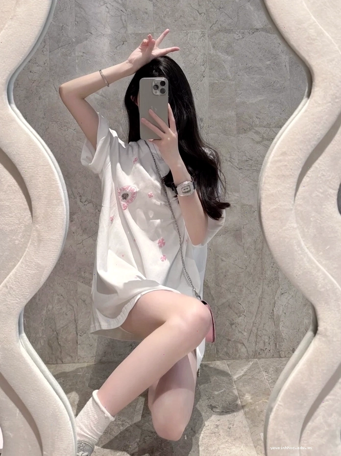Cô gái xinh đẹp tự chụp ảnh với điện thoại che mặt trước gương