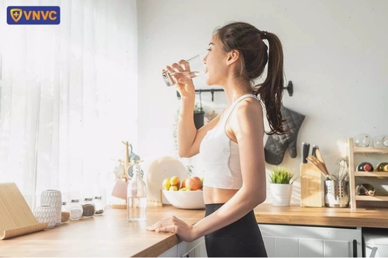 Ly nước lọc trong veo đặt cạnh các loại trái cây tươi