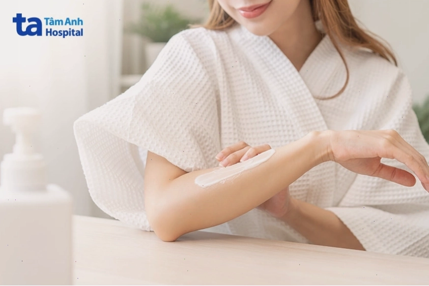 Phụ nữ đang thoa kem dưỡng làm dịu da khi bị kích ứng hoặc nổi mẩn, giúp giảm ngứa và phục hồi da