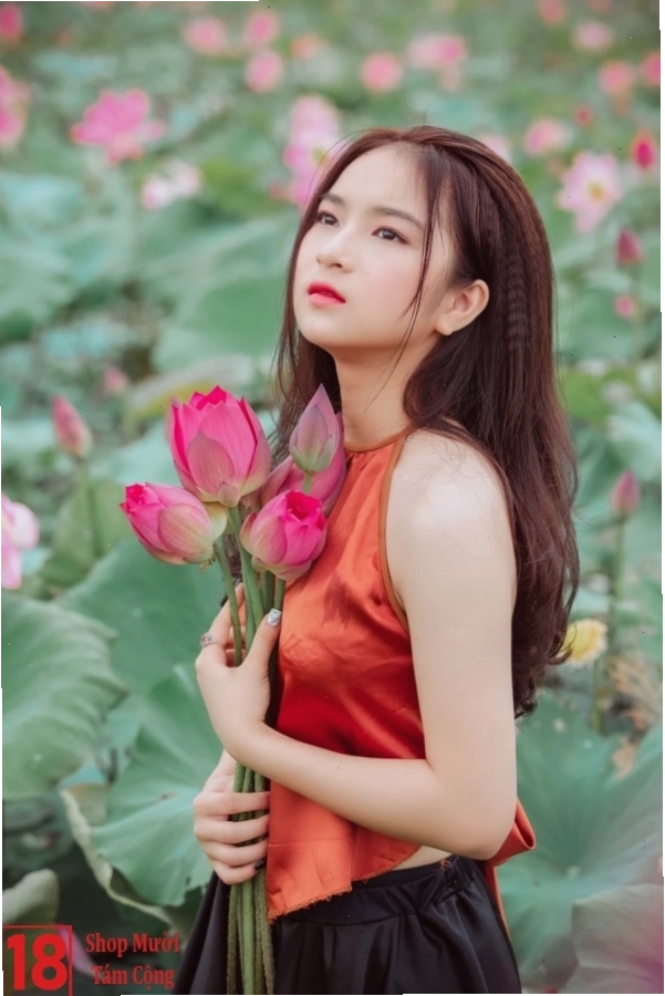Thiếu nữ trong tà áo dài trắng thanh lịch, tay cầm bó hoa sen hồng phớt